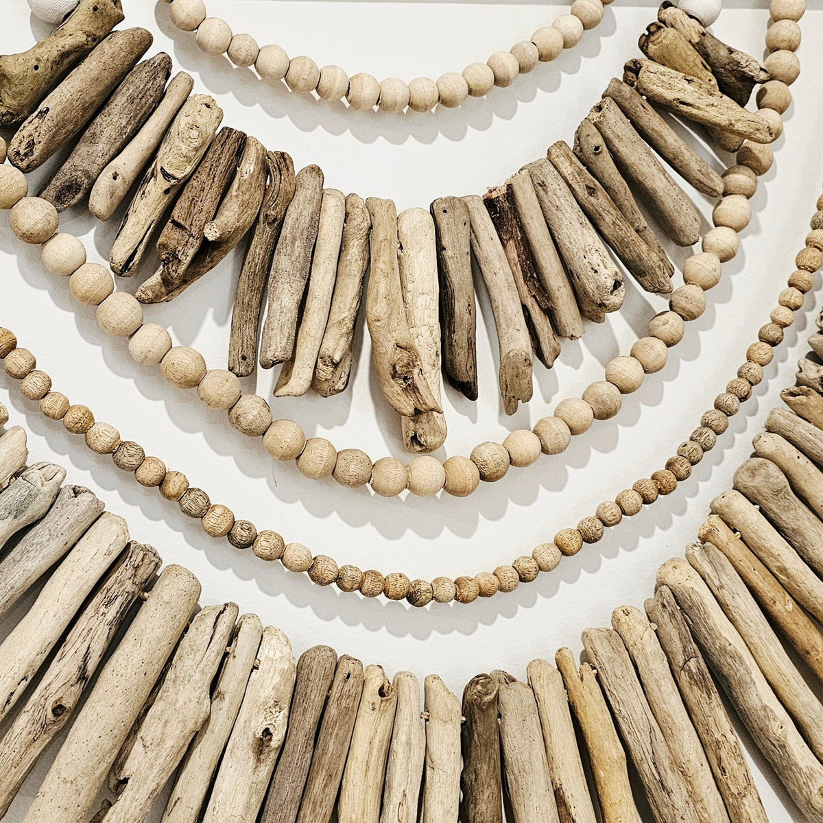 Driftwood and bead necklace on a white background