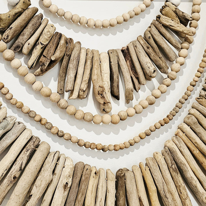 Driftwood and bead necklace on a white background