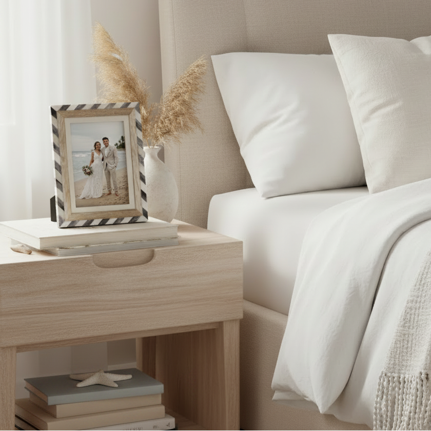 A rectangular picture frame with a striped border in black and white, featuring a light natural wood inner frame and a cream mat. 