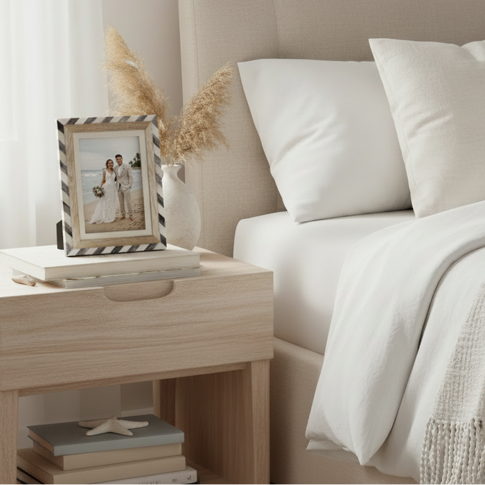 A rectangular picture frame with a striped border in black and white, featuring a light natural wood inner frame and a cream mat. 