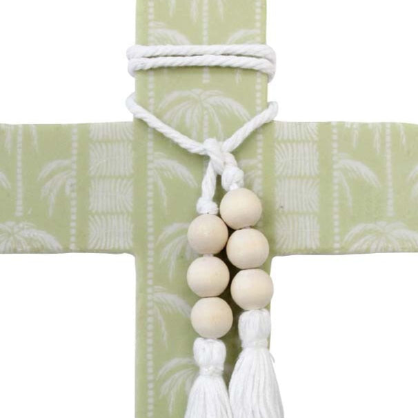 Decorative cross with beads and tassels on a light green background