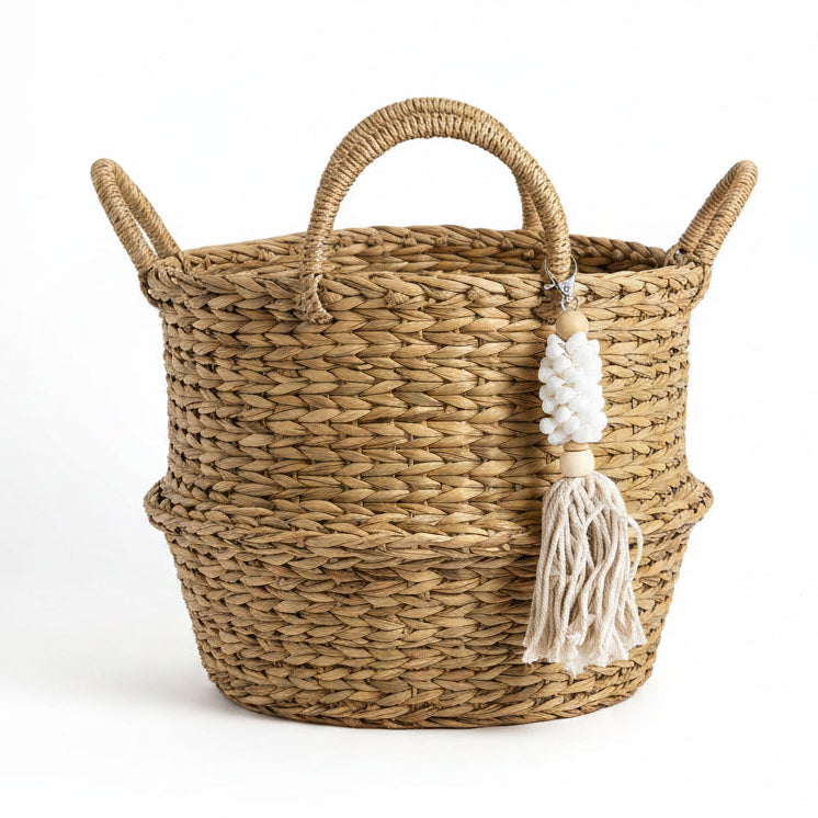 A bohemian-style keychain or bag charm featuring a white seashell spiral, light wood beads, and a cream macrame tassel, 
