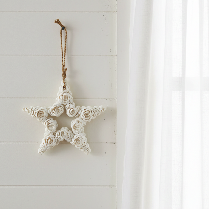 A handmade balinese white shell star-shaped hanging ornament with a brown cord loop at the top coastal home decor