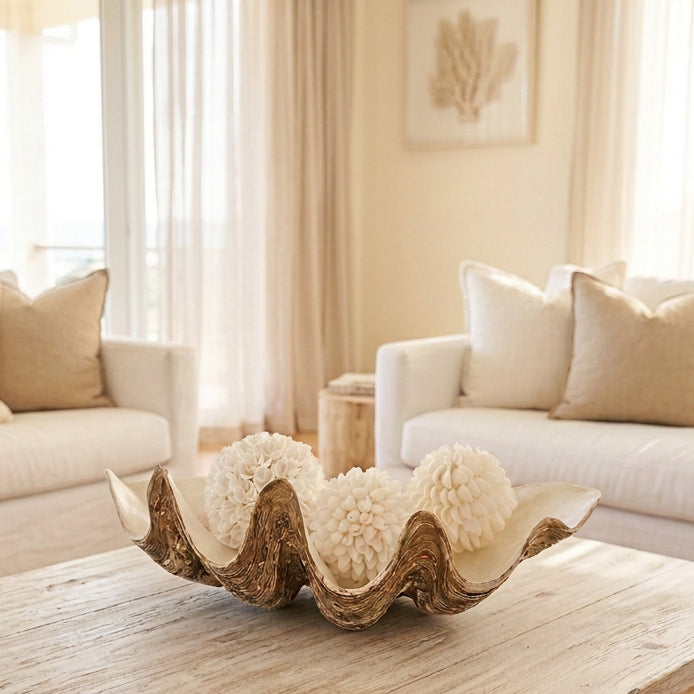 A decorative shell-shaped tray holding three DECORATIVE HANDMADE BALINESE SHELL BALLS
