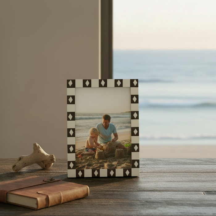 A rectangular picture frame with a cream and dark brown checkered border featuring repeating diamond motifs. 
